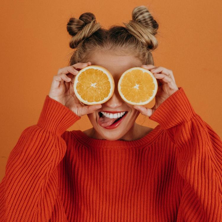 Girl with oranges over her eyes